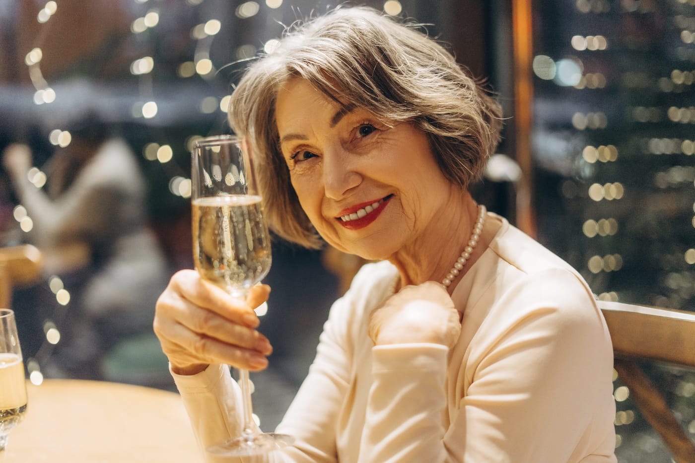 Elegant senior woman enjoying champagne in festive atmosphere